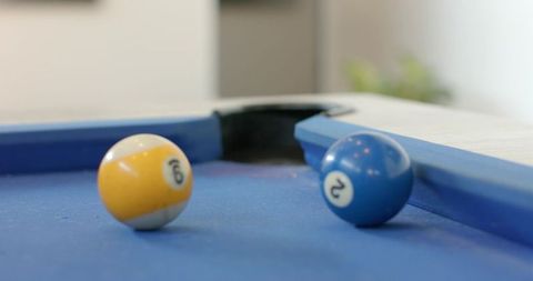 Resting glossy 9 and 2 billiard balls on blue-felt pool table near corner pocket