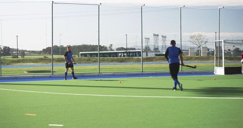 Hockey Players Practicing on Turf Field Under Clear Sky