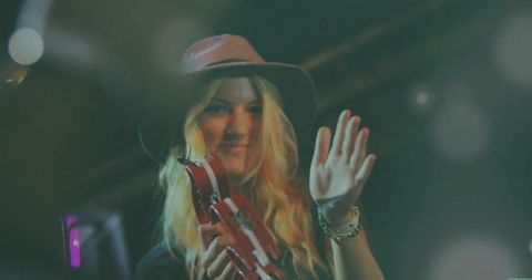 Energetic performer at concert with tambourine and hat