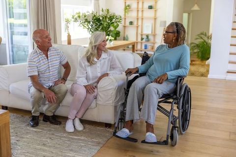 Senior Friends Chatting in Cozy Living Room with Wheelchair
