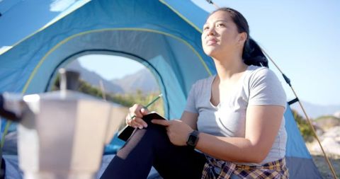 Woman Journaling by Tent in Mountain Camping Adventure
