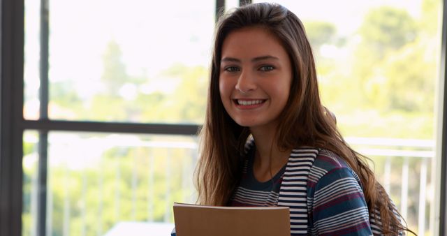 Smiling Female Student Holding Notebook in Bright Modern Classroom - Download Free Stock Images Pikwizard.com