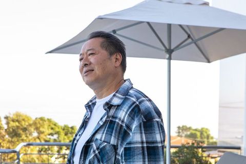 Relaxed Asian Man on Balcony Looking at Urban Skyline
