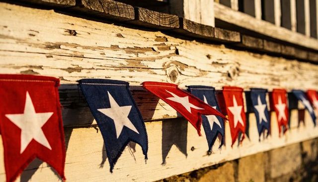 Weathered porch draping red and blue star pennant garland fluttering in golden sunlight