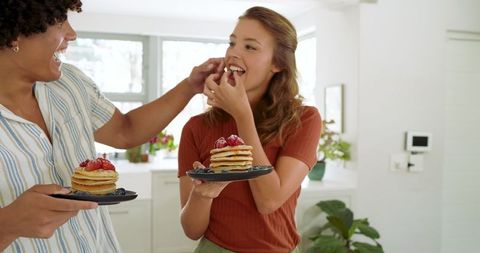 Couple Enjoying Pancakes with Fresh Berries in Sunny Kitchen