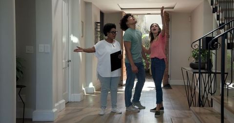 Diverse couple viewing modern home with real estate agent