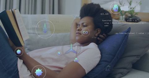 Young woman reclining and reading on sofa with augmented reality hud showing health data