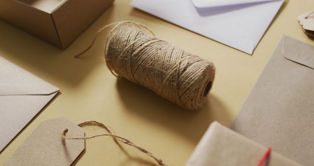 This image shows various eco-friendly brown packaging supplies spread out on a table. Items include envelopes, tags, and a spool of twine. Ideal for use in articles or materials focused on sustainable packaging, crafts, or minimalism.