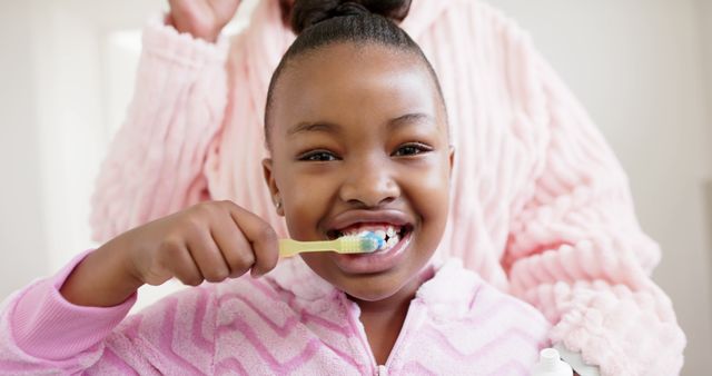 Smiling Young Girl Brushing Teeth with Supportive Parent Nearby - Download Free Stock Images Pikwizard.com