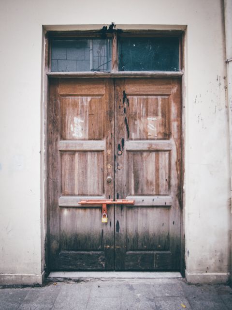 The weathered appearance of the door suggests age and history, contributing to an urban, vintage feel. Great for use in projects related to architecture, urban decay, historic building renovation, or street photography. It serves as a powerful visual metaphor for subjects such as closure, security, and forgotten places.
