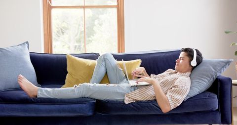 Relaxed Young Man with Headphones Using Laptop on Comfortable Couch - Download Free Stock Images Pikwizard.com