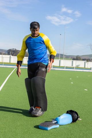Teen goalkeeper preparing: active youth with protective gear on turf