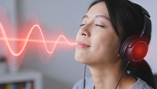 Serene woman listening with red headphones and glowing waveform, closeup wellness portrait