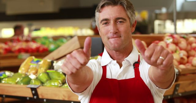 Portrait of smiling worker doing thumbs up in grocery store