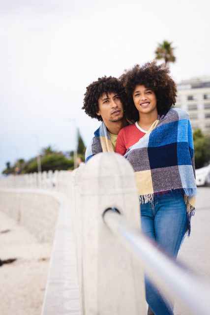 Romantic afro african american young couple wrapped in blanket against sky, copy space. unaltered, lifestyle, love and togetherness concept.