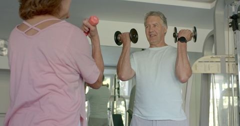 Senior couple exercising together with dumbbells for health
