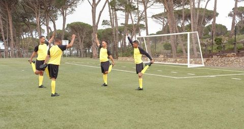 Soccer Players in Yellow Uniforms Stretching on Field