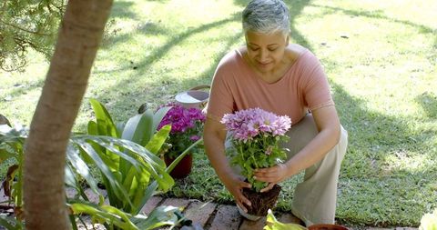 Senior Woman Joyfully Gardening in Lush Home Garden