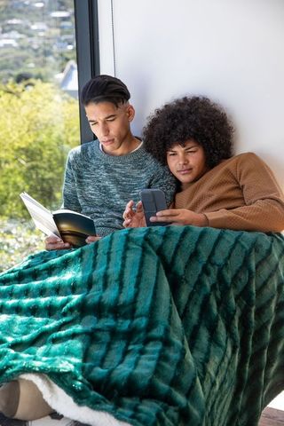 Diverse Friends Relaxing with Book and Smartphone at Home