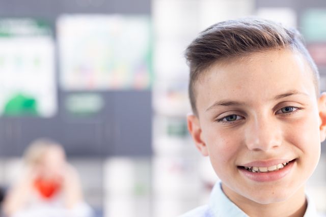 This image depicts a smiling Caucasian boy in an elementary school classroom. The background is slightly blurred, focusing on the boy's cheerful expression. Ideal for educational materials, school brochures, websites, and advertisements promoting positive learning environments and childhood education.