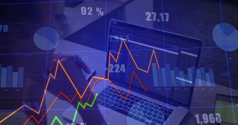 Analyst reviewing laptop with dynamic trading charts and analytics dashboard overlays