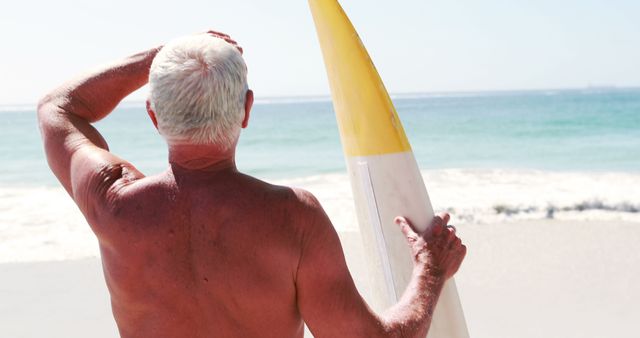 An elderly man pauses with his surfboard on the beach, poised for a surf. - Download Free Stock Photos Pikwizard.com