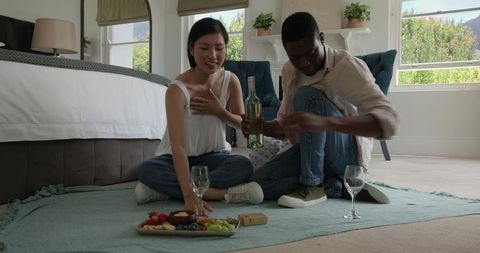 Couple Enjoying Romantic Picnic Indoors with Wine and Snacks