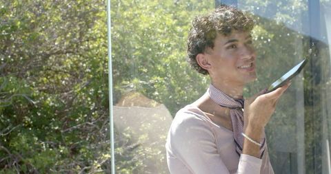 Man Enjoying Voice Assistance on Smartphone in Sunny Garden