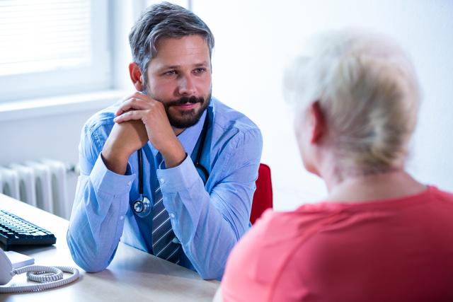 Doctor consulting a senior patient in a hospital office. The doctor is attentively listening to the patient, providing medical advice and care. This image can be used for healthcare websites, medical blogs, patient care brochures, and hospital promotional materials.