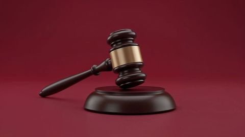 Judge's gavel resting on burgundy backdrop symbolizing justice and authority