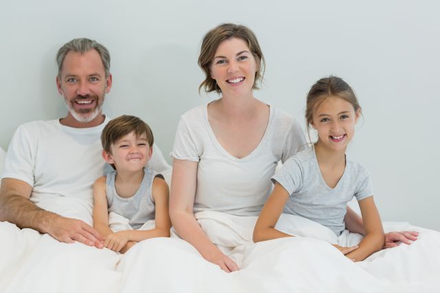 Portrait of happy family sitting together on bed in bedroom at home