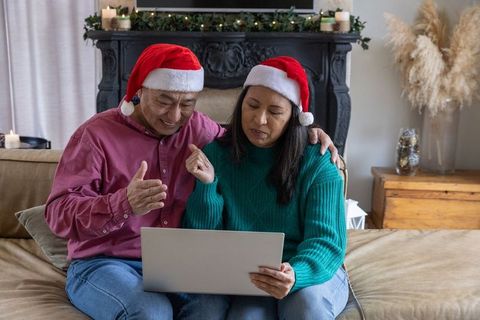 Asian Couple Enjoying Holiday Video Call with Laptop in Cozy Living Room