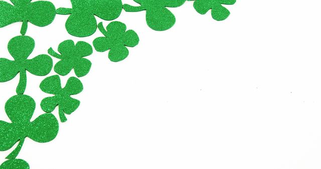 Decorative sparkling green shamrocks arranged on a white surface, common for adding festive elements to St. Patrick's Day and Irish-themed designs. Suitable for holiday promotions, greeting cards, event flyers, and social media posts celebrating Irish culture and heritage.