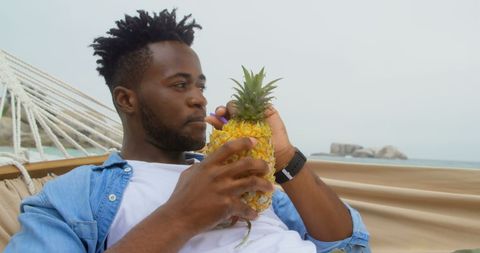 Man Enjoying Refreshing Pineapple Drink on Tropical Beach