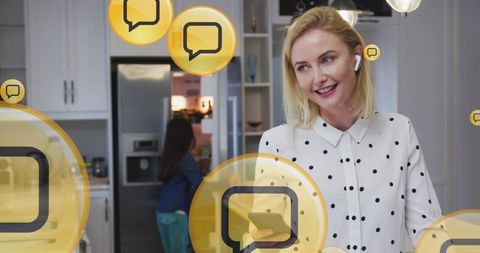 Mother Joyously Engaging with Smartphone and Digital Icons in Modern Kitchen