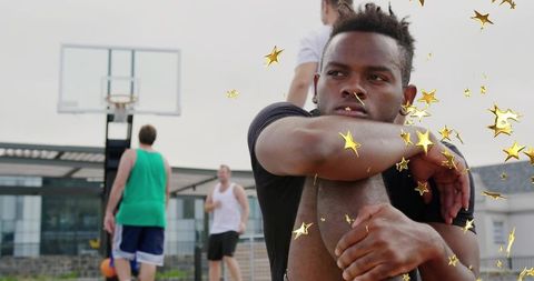 Young athlete relaxing on rooftop basketball court outdoors