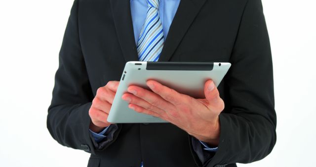 A businessman dressed in a suit and tie is using a digital tablet, focusing on his hands and the tablet against a white background. This image is perfect for illustrating concepts related to corporate communications, digital business solutions, technology in the workplace, and modern professional environments. Ideal for use in business presentations, technology promotions, corporate websites, and professional blogs.