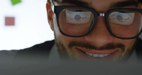 Focused professional analyzing data reflected in glasses