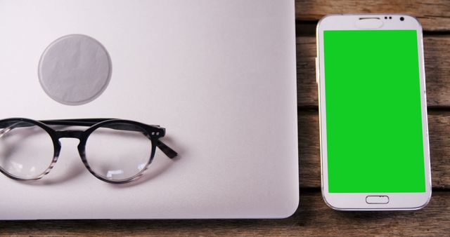 Laptop with Glasses and Smartphone with Green Screen on Wooden Table - Download Free Stock Images Pikwizard.com