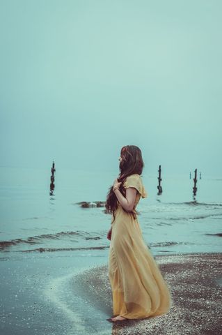 Dreamy Young Woman Strolling by Tranquil Ocean