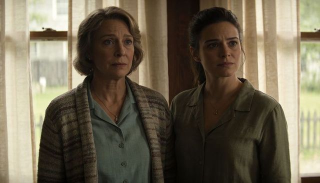 Mother and daughter standing by window offering comfort and support, intergenerational bond