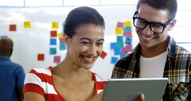 Young Professionals Smiling While Looking at Tablet in Modern Office - Download Free Stock Images Pikwizard.com