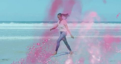 Carefree Woman Walking on Beach with Pink Powder Splash