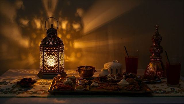 Ornate Moroccan lantern casting intricate shadows over sweets tray in warm amber glow