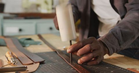 Hands creating leatherware in artisan workshop