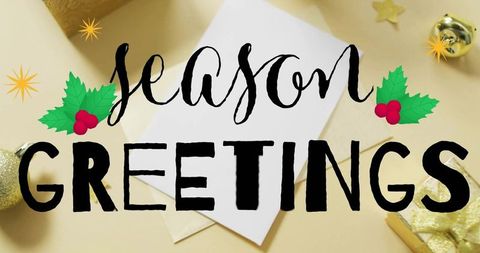 Season greetings card featuring holly, envelope, gold baubles, glitter gift wrap flatlay