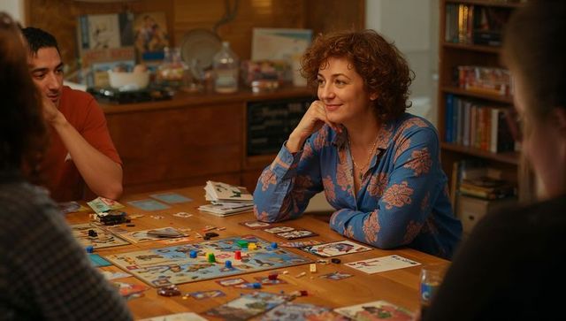 Curly-haired woman smiling while playing board game during cozy home game night
