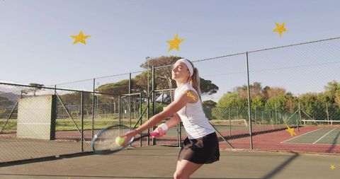 Female tennis player swinging forehand on sunlit outdoor court showing focus and determination