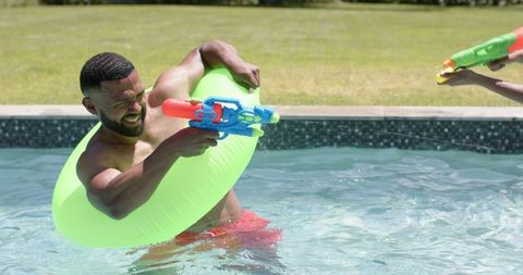 Father and Daughter Enjoying Pool Water Gun Fight