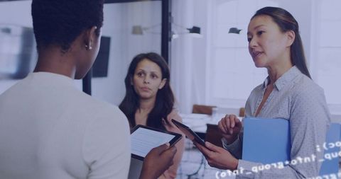 Women Collaborating with Tablets in Modern Office Glass-Partition Business Meeting